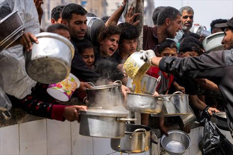 People queue with pots to receive charity meals from a kitchen in Beit Lahia in the northern Gaza Strip on April 24, 2025 (AFP photo)